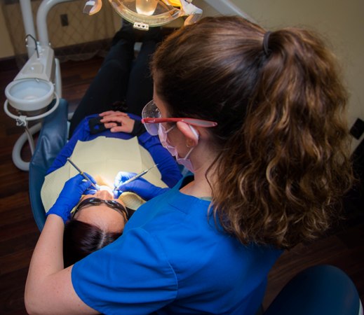 hygienist at South Natick Dental performing teeth cleaning for patient