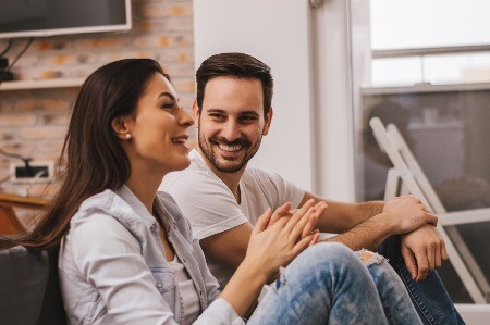 smiling happy couple sitting in their apartment